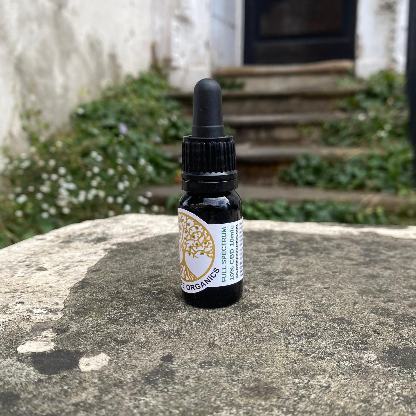 Bottle of organic spectrum oil on a stone surface with a garden background