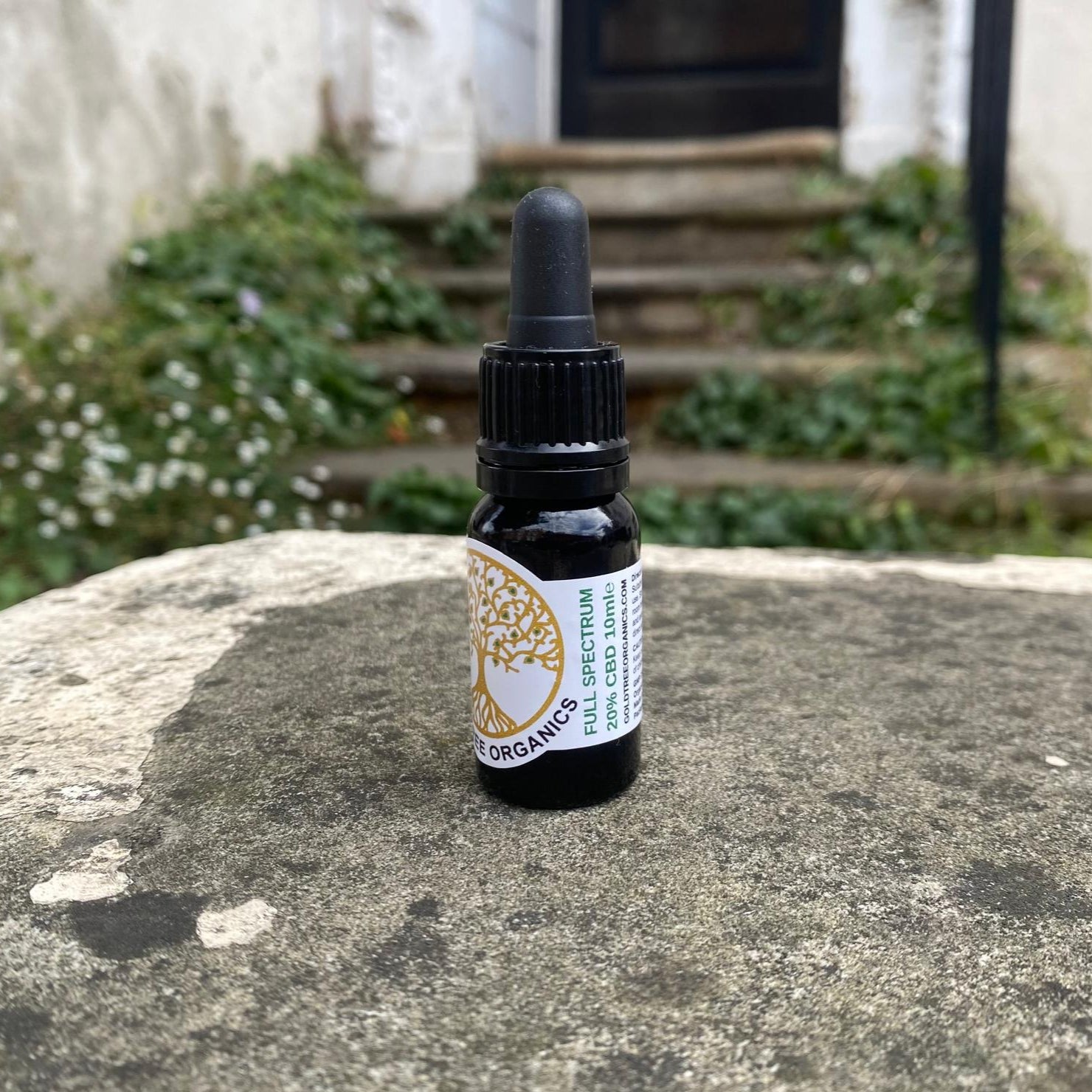 Small black bottle with dropper on a stone surface outdoors