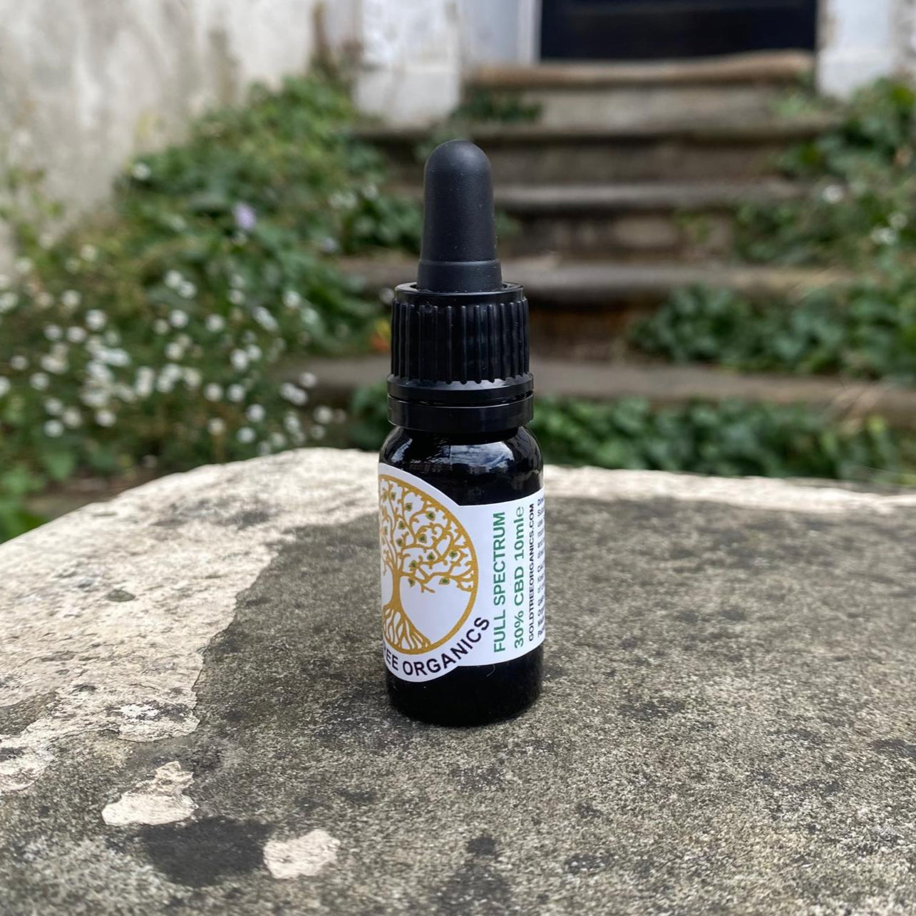 Bottle of organic full-spectrum product on a stone surface with a garden background
