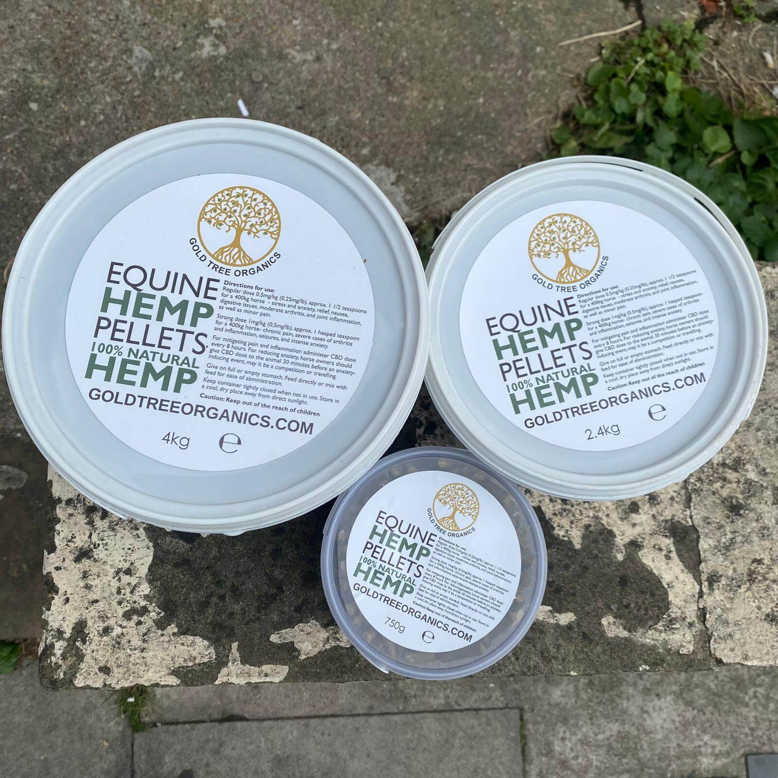 Three sizes of Gold Tree Organics equine hemp pellets in white containers for horse health