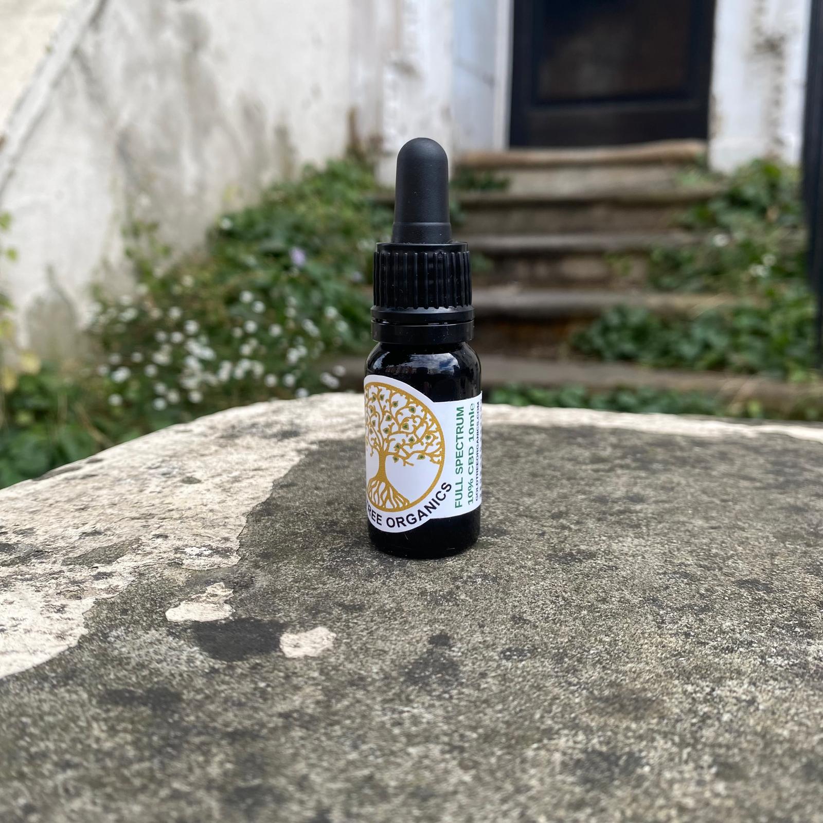 Gold Tree Organics full spectrum CBD oil in a dropper bottle on a stone surface