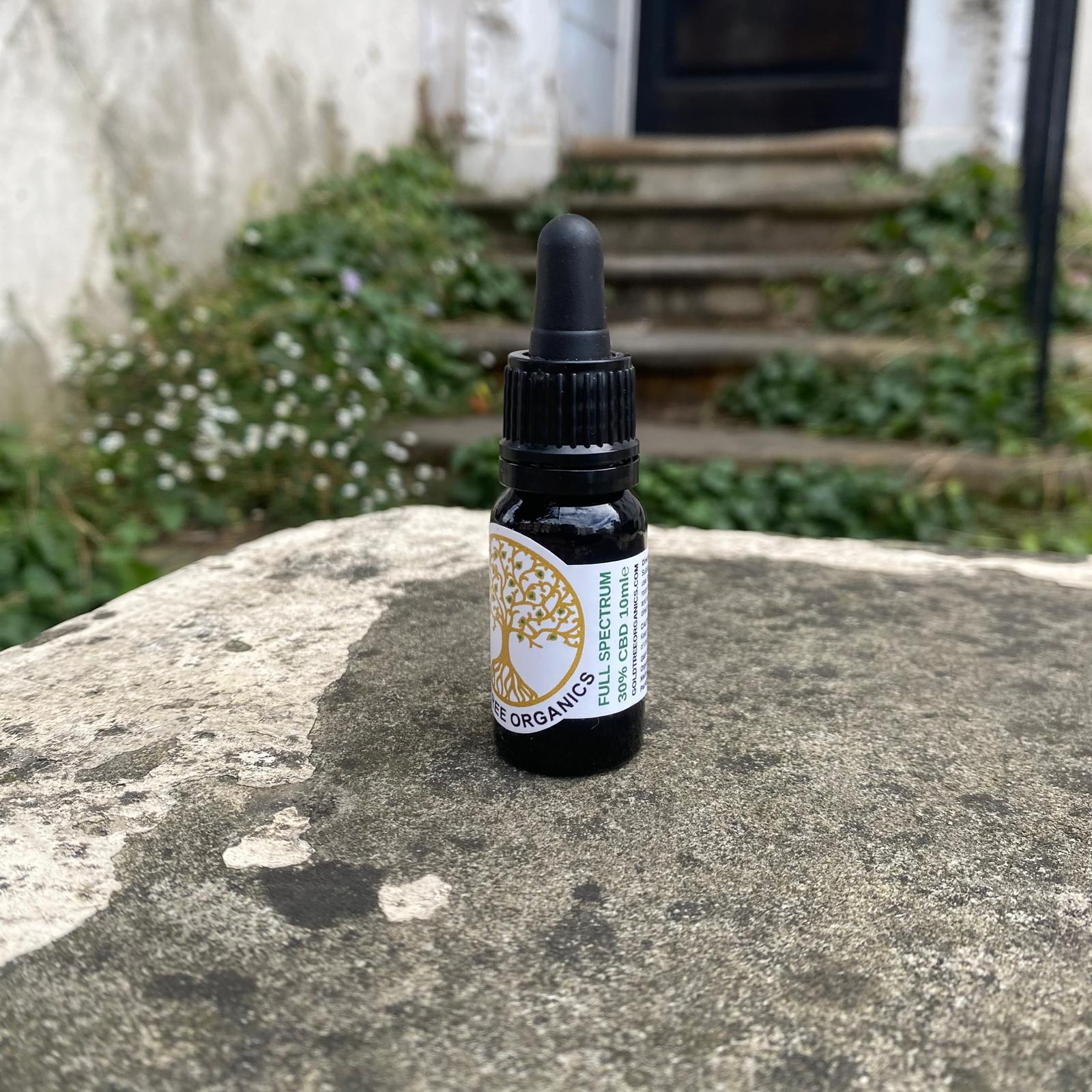 Gold Tree Organics full spectrum CBD oil bottle placed on a stone surface outdoors