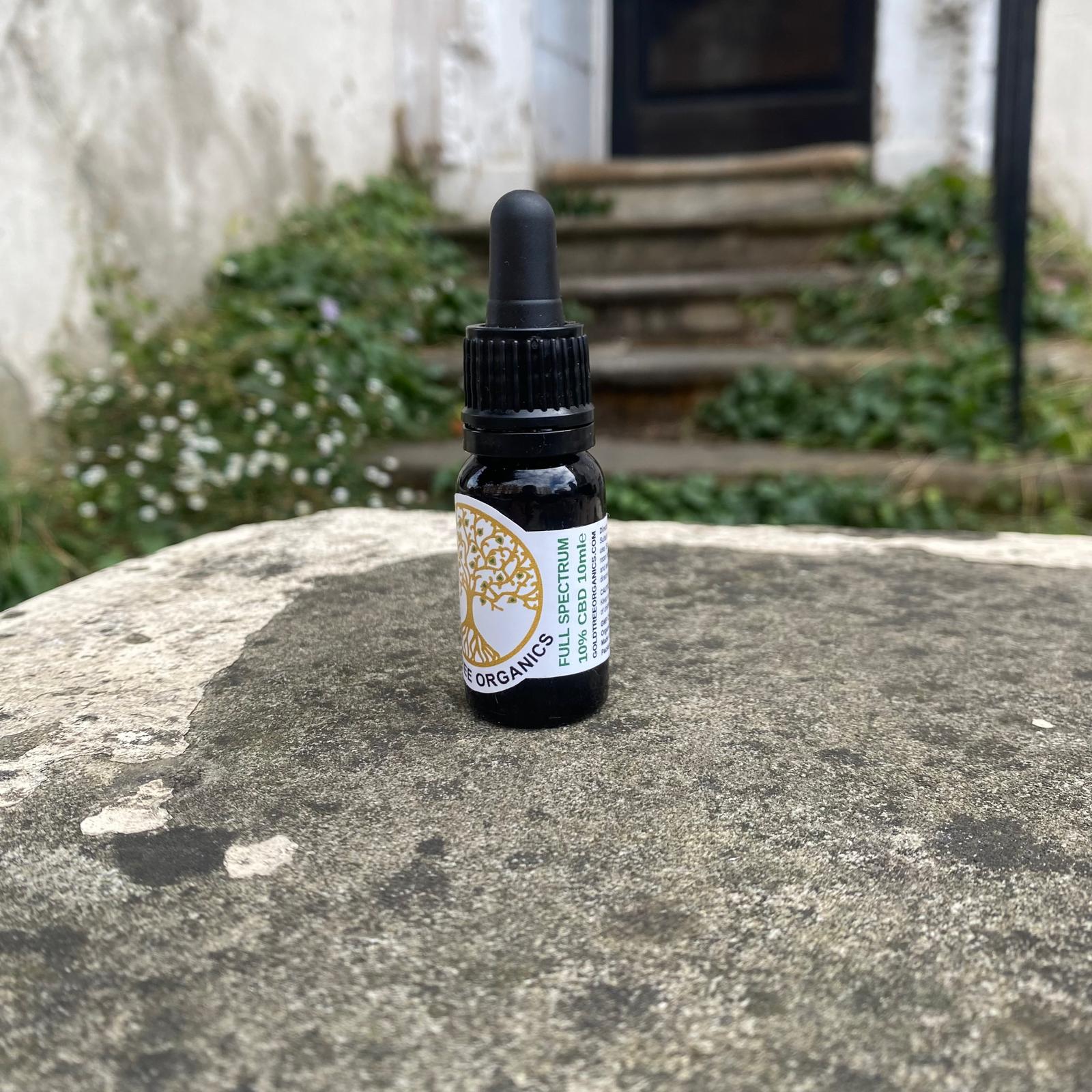 Gold Tree Organics full spectrum CBD oil dropper bottle on a stone surface