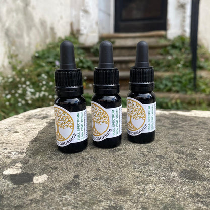 Three bottles of Gold Tree Organics full spectrum CBD oil placed on a stone surface outdoors